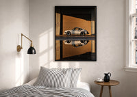 White 911 Hangar Sunset Reflection print in a black frame above a bed with striped linens