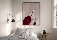 White Sneakers with Burgundy Trousers print in a black frame above a bed with striped linens