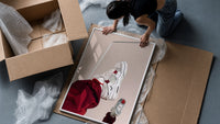White Sneakers with Burgundy Trousers framed print being unpacked from protective bubble wrap and a box
