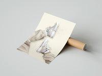 Gently curled White Sneakers with Cream Trousers print beside its protective shipping tube
