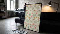 Vintage floral pattern with daisies print in a slim black frame leaning on a dark sofa in a concrete print studio