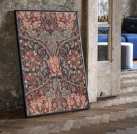 Ornate floral honeysuckle pattern print in a black frame leaning beside a vintage door on parquet