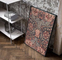 Ornate floral honeysuckle pattern poster in a black frame leaning beside a shelf in a raw-plaster loft