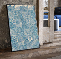 Floral marigold pattern with leaves print in a black frame leaning beside a vintage door on parquet