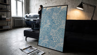 Floral marigold pattern with leaves print in a slim black frame leaning on a dark sofa in a concrete print studio