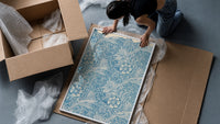 Floral marigold pattern with leaves framed print being unpacked from protective bubble wrap and a box
