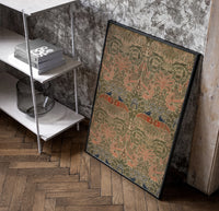 Floral bird damask textile pattern poster in a black frame leaning beside a shelf in a raw-plaster loft