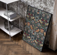 Birds and strawberries floral pattern poster in a black frame leaning beside a shelf in a raw-plaster loft