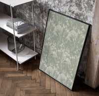 Ornate floral tulip leaf pattern poster in a black frame leaning beside a shelf in a raw-plaster loft