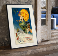 Witch riding broomstick past moon print in a black frame leaning beside a vintage door on parquet