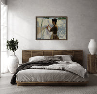 Woman hanging laundry outdoors print in a dark wood frame above a rattan bed on a plaster wall