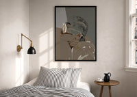Woman in Heart Hoops and Sunglasses print in a black frame above a bed with striped linens