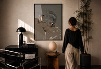 Woman in Heart Hoops and Sunglasses print in a black frame on a sunlit wall with a viewer