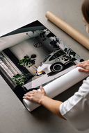 Woman unrolling a Porsche 911 Classic White Industrial Loft poster print on a concrete floor