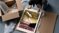 Erupting volcano over lake framed print being unpacked from protective bubble wrap and a box