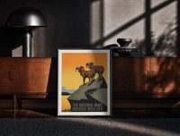 Black-framed Two bighorn sheep on rocky cliff print on a moody console with designer coffee-table books