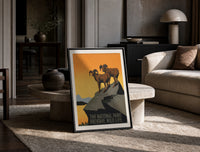 Two bighorn sheep on rocky cliff print in a black frame leaning on a travertine table in a sunlit lounge