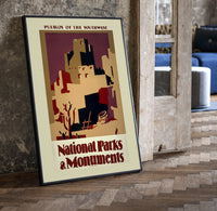 Southwest pueblo cliff dwellings print in a black frame leaning beside a vintage door on parquet