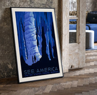 Cave stalactites with two tourists print in a black frame leaning beside a vintage door on parquet