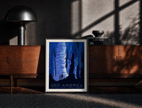 Black-framed Cave stalactites with two tourists print on a moody console with designer coffee-table books