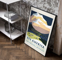 Snowy mountain with Native American camp poster in a black frame leaning beside a shelf in a raw-plaster loft