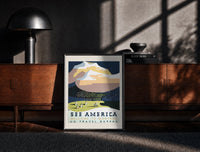 Black-framed Snowy mountain with Native American camp print on a moody console with designer coffee-table books
