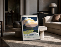 Snowy mountain with Native American camp print in a black frame leaning on a travertine table in a sunlit lounge