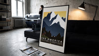 Cowboy on horse viewing mountains print in a slim black frame leaning on a dark sofa in a concrete print studio